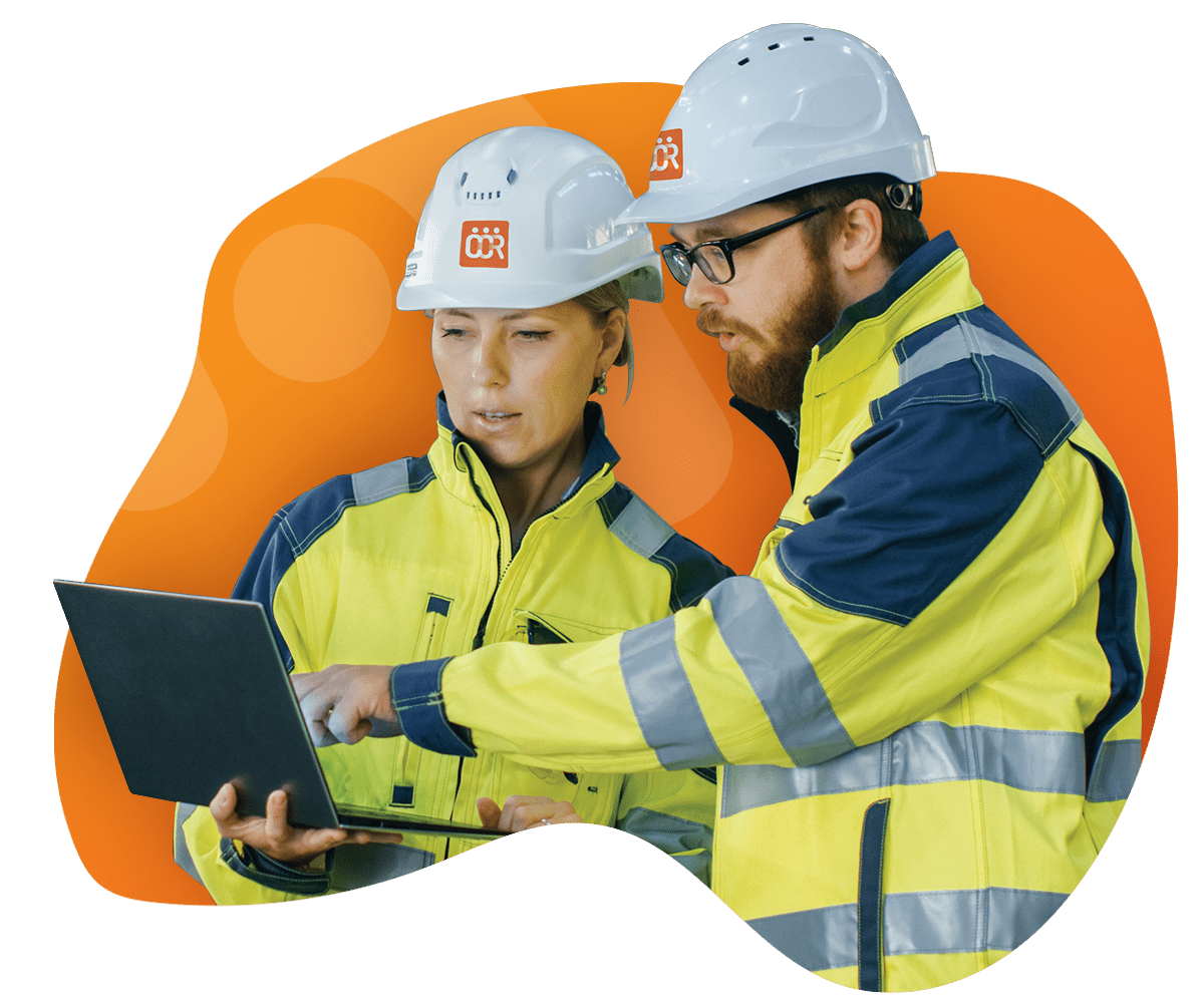 Two construction workers in safety helmets and high-visibility jackets look at a laptop, discussing the latest CCR updates.