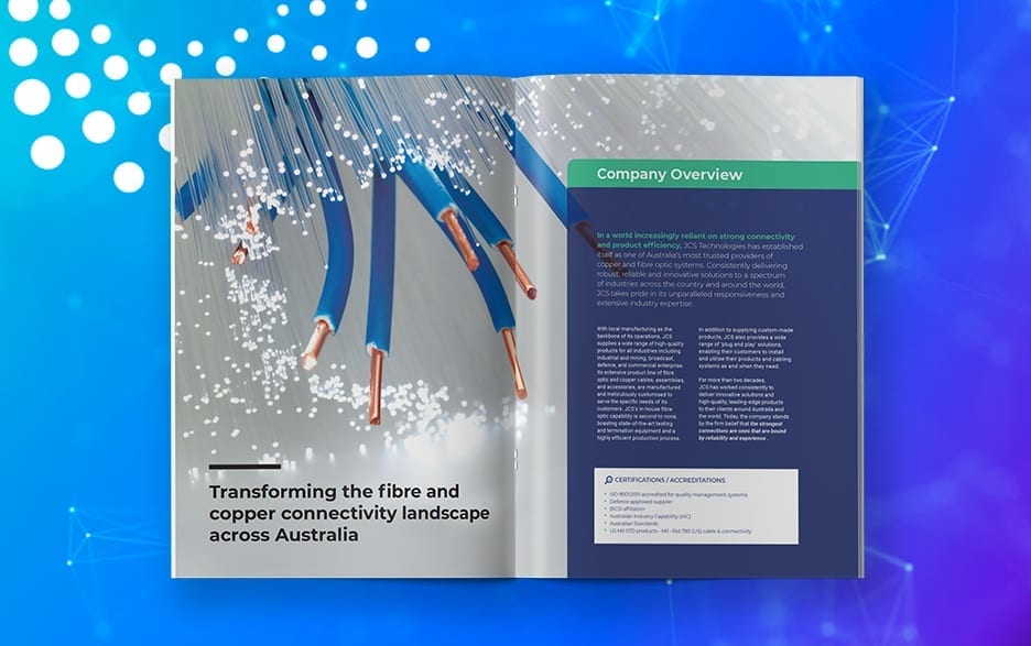 An open magazine displays an article about JCS transforming fiber and copper connectivity in Australia. The left page has an image of fiber cables, and the right page has text under "Company Overview.