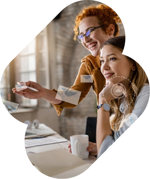 Two businesswomen in an office are reviewing documents, one pointing at papers while the other holds a cup. Email icons are overlaid on the image, symbolizing their discussion about email marketing strategies.